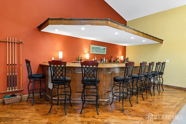 bar featuring wood finished floors, high vaulted ceiling, baseboards, indoor bar, and recessed lighting