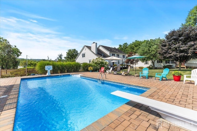 view of swimming pool featuring a fenced in pool, a diving board, a patio, and fence