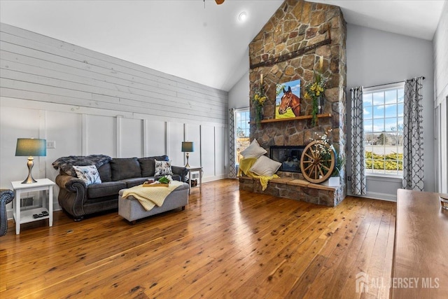 living area with a fireplace, high vaulted ceiling, and hardwood / wood-style flooring