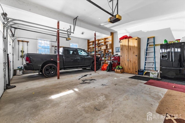 garage with a garage door opener and black refrigerator with ice dispenser