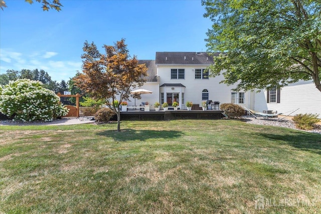 back of property with fence, a yard, and a deck