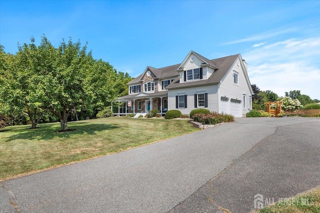 view of front facade featuring a garage, a front yard, covered porch, and driveway