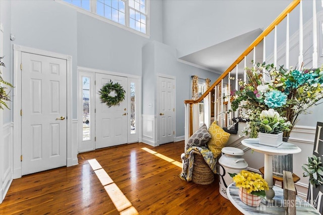 foyer with stairway, a wealth of natural light, hardwood / wood-style flooring, and a towering ceiling