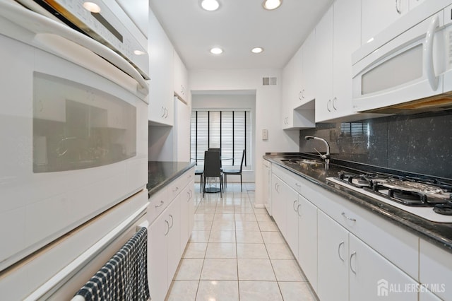 kitchen with light tile patterned floors, white appliances, a sink, visible vents, and decorative backsplash