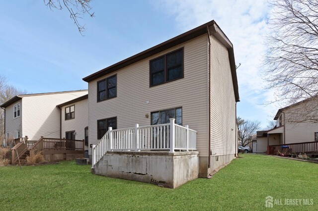 rear view of property featuring a lawn and a deck