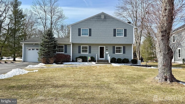 colonial home featuring a garage, driveway, central AC unit, and a front yard