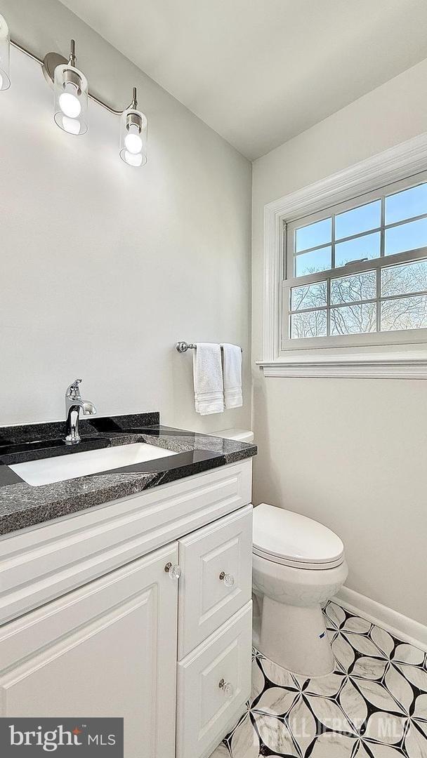 bathroom with toilet, tile patterned flooring, vanity, and baseboards