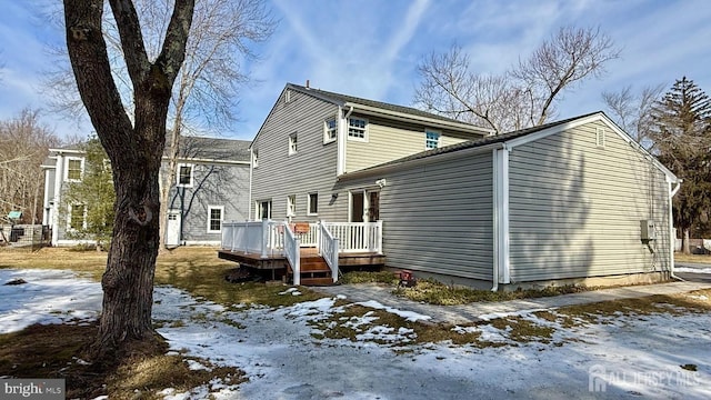 snow covered rear of property with a wooden deck