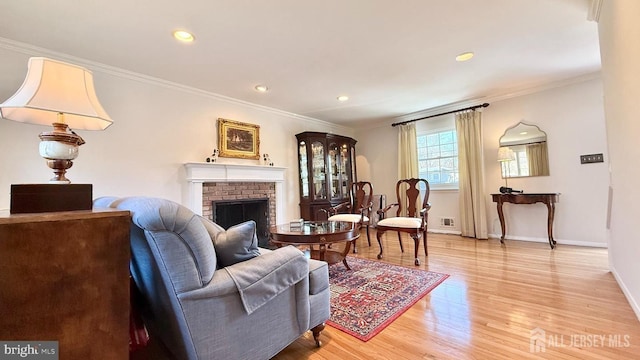 sitting room with baseboards, a fireplace, wood finished floors, and crown molding