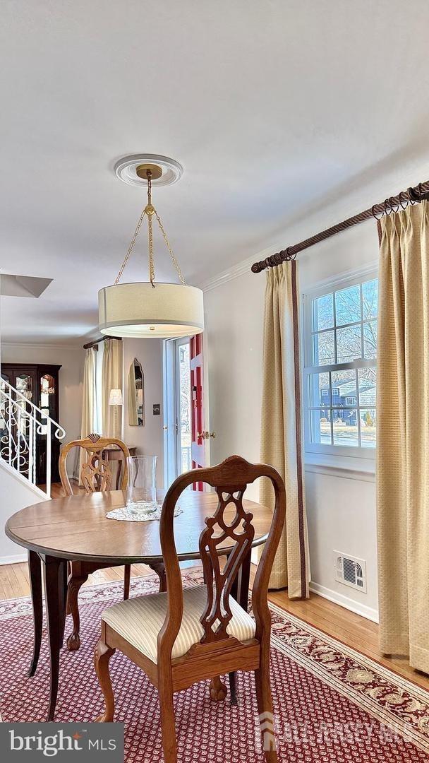 dining space with visible vents, crown molding, baseboards, and wood finished floors