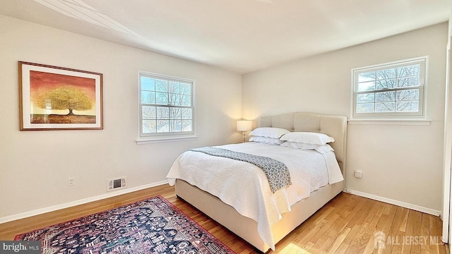 bedroom with wood finished floors, visible vents, and baseboards