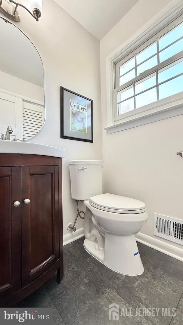 bathroom featuring toilet, baseboards, visible vents, and vanity