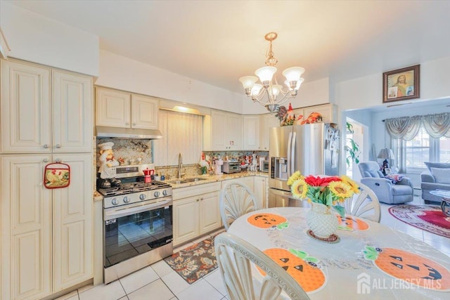 kitchen with appliances with stainless steel finishes, backsplash, sink, hanging light fixtures, and light tile patterned flooring