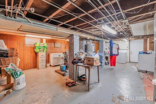 basement featuring washer / clothes dryer, wooden walls, water heater, and white refrigerator