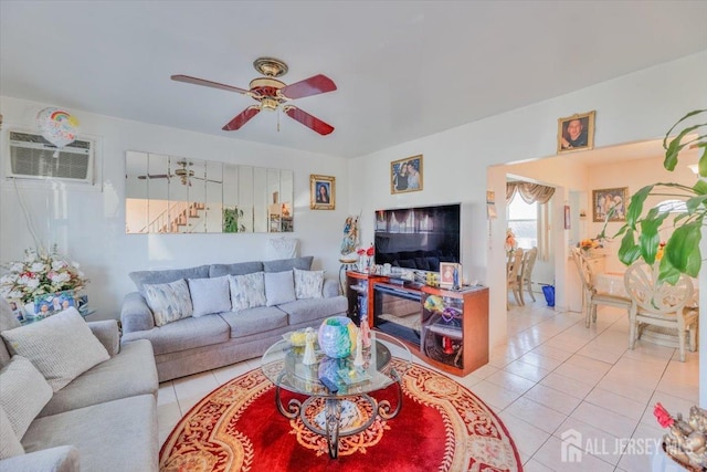 living room featuring a wall mounted air conditioner, light tile patterned floors, and ceiling fan