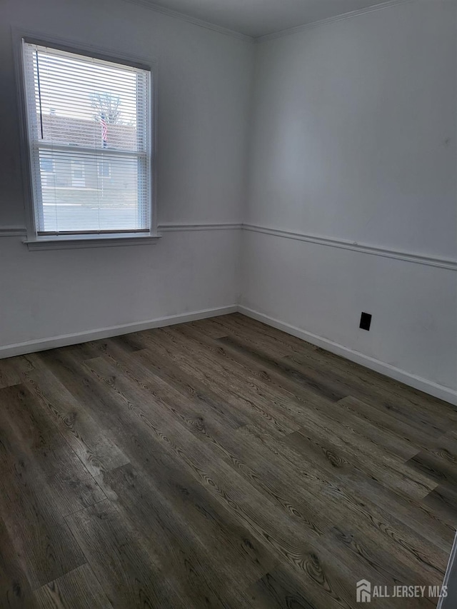 spare room with baseboards and wood finished floors