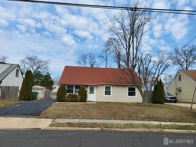 new england style home with a front yard, driveway, and fence