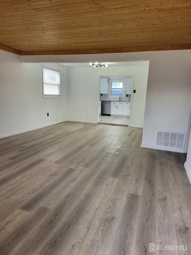 empty room with visible vents, lofted ceiling, a sink, light wood-style floors, and wood ceiling