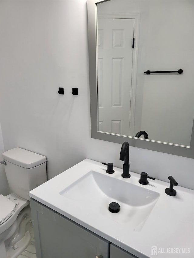 half bathroom featuring vanity, toilet, and marble finish floor