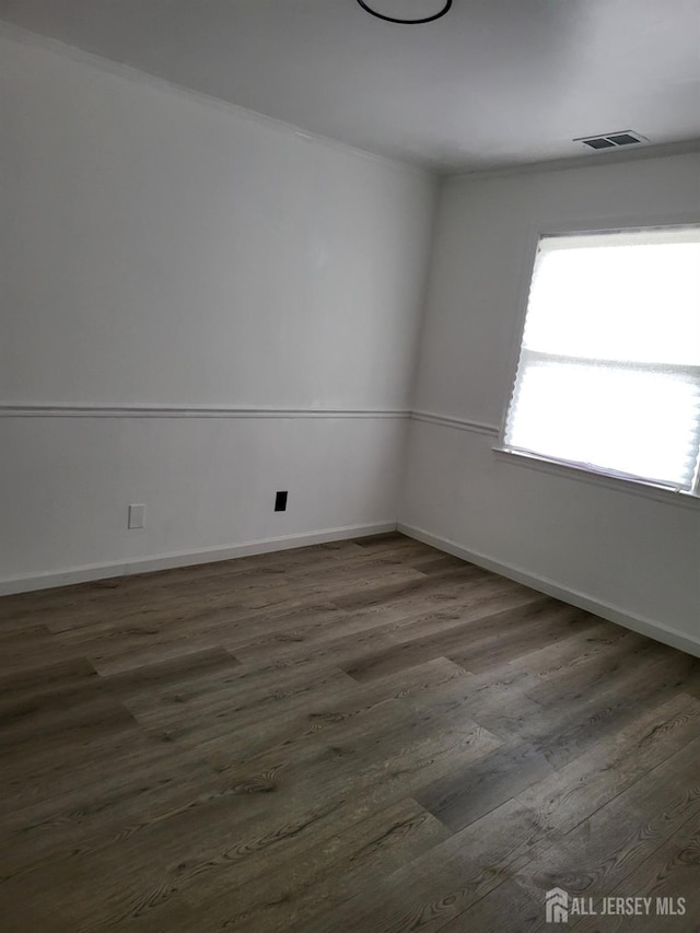 unfurnished room with dark wood-style floors, visible vents, and baseboards