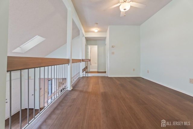 spare room with hardwood / wood-style flooring, ceiling fan, and vaulted ceiling with skylight