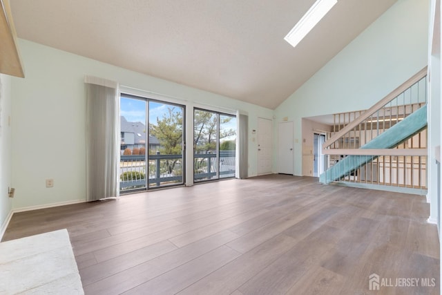 unfurnished living room with high vaulted ceiling and light hardwood / wood-style floors