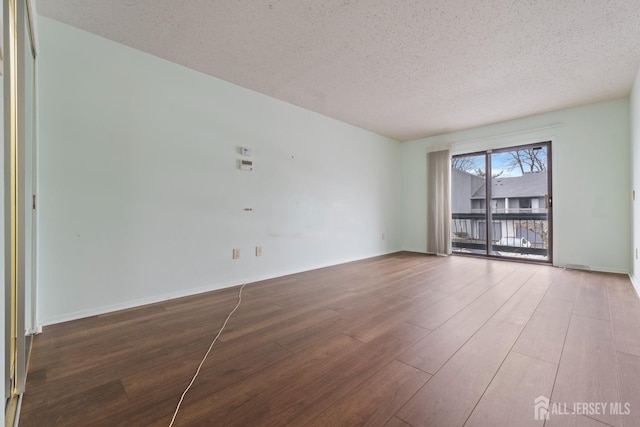 empty room with hardwood / wood-style flooring and a textured ceiling