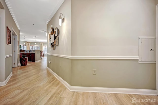 corridor featuring electric panel, baseboards, crown molding, light wood-style floors, and a sink