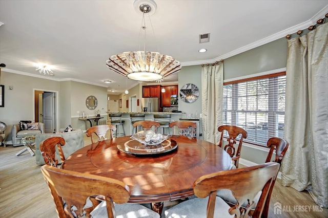 dining room with visible vents, crown molding, light wood-style flooring, and baseboards