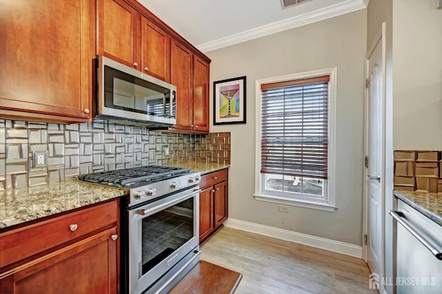 kitchen featuring stainless steel appliances, backsplash, and light stone counters