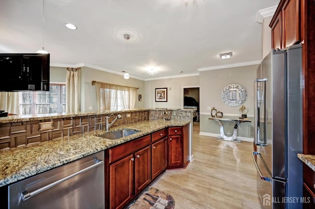 kitchen featuring ornamental molding, appliances with stainless steel finishes, a sink, and light stone counters