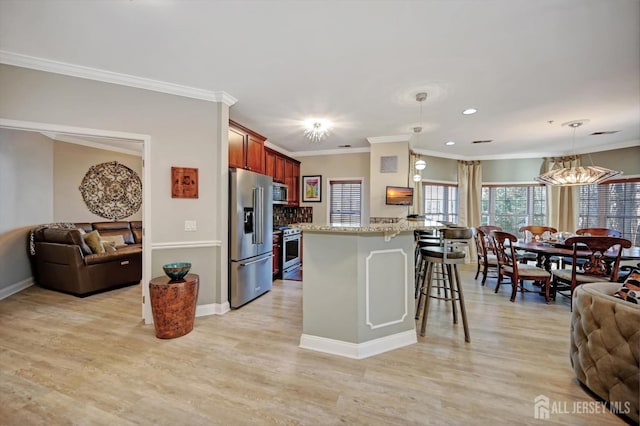 kitchen with open floor plan, stainless steel appliances, hanging light fixtures, and light stone counters