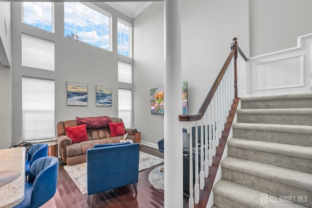 living room with a towering ceiling, hardwood / wood-style flooring, and ornamental molding