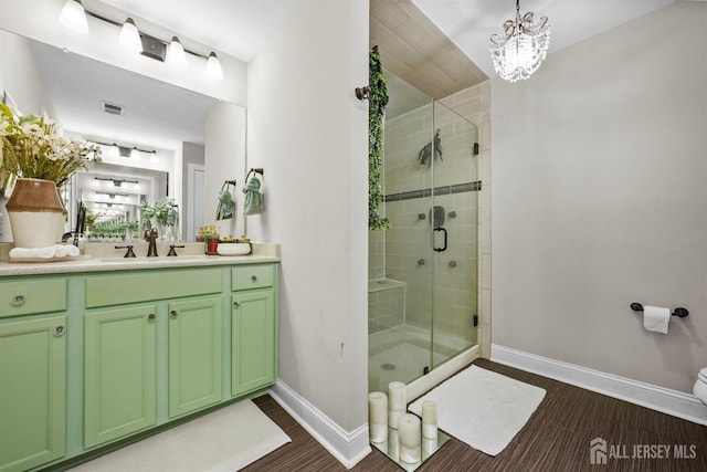 bathroom featuring a chandelier, wood-type flooring, vanity, and an enclosed shower