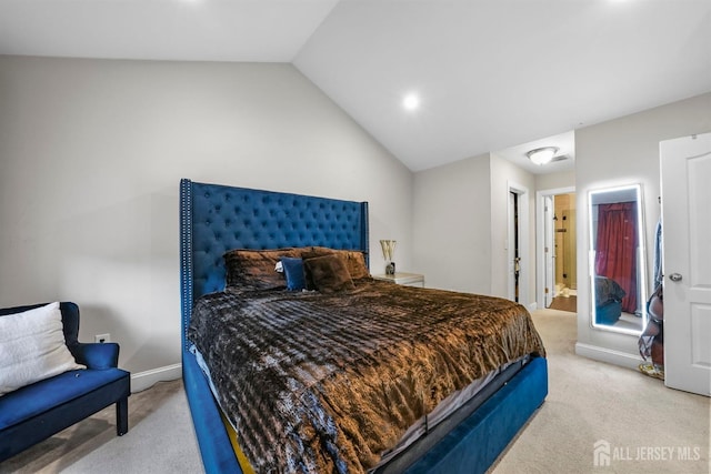 bedroom with ensuite bathroom, lofted ceiling, and light carpet