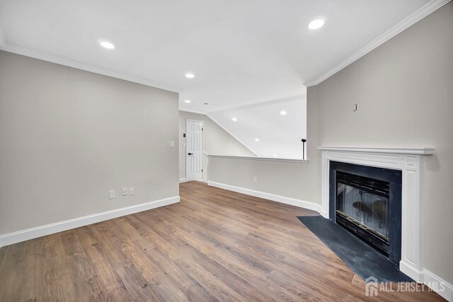 unfurnished living room with baseboards, wood finished floors, crown molding, recessed lighting, and a fireplace with flush hearth