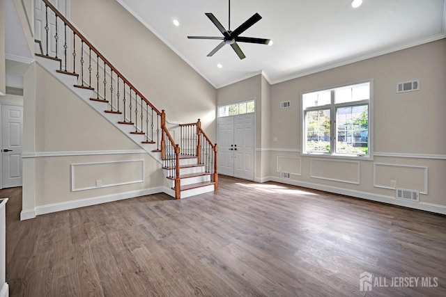 unfurnished living room with crown molding, stairway, ceiling fan, dark wood-type flooring, and vaulted ceiling