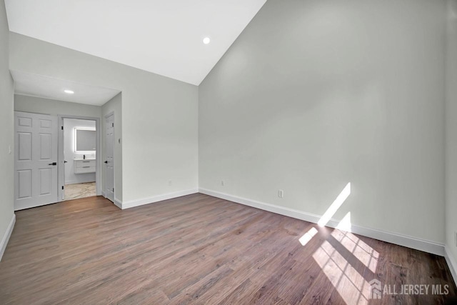 unfurnished bedroom featuring baseboards, wood finished floors, lofted ceiling, and recessed lighting