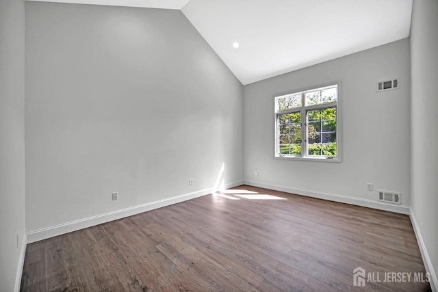 unfurnished room with lofted ceiling, wood finished floors, and baseboards