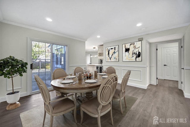 dining space with crown molding, wood finished floors, recessed lighting, a decorative wall, and baseboards