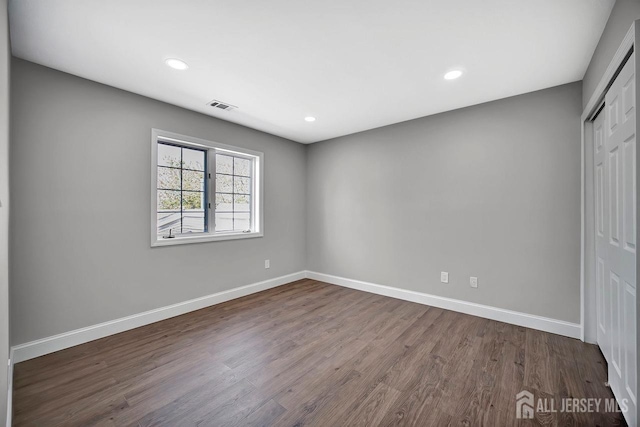 unfurnished bedroom with a closet, baseboards, dark wood-style floors, and recessed lighting