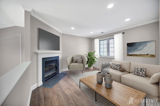 living area with wood finished floors, recessed lighting, a fireplace with flush hearth, baseboards, and crown molding