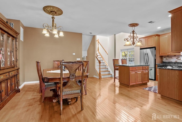 dining area featuring light wood-type flooring and a notable chandelier