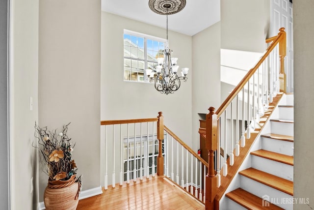 staircase with hardwood / wood-style floors and a notable chandelier