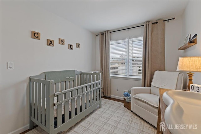 bedroom featuring a crib, baseboards, and wood finished floors