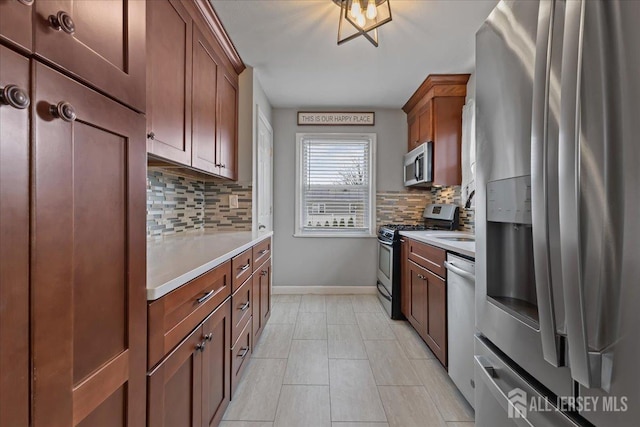 kitchen featuring appliances with stainless steel finishes, light countertops, tasteful backsplash, baseboards, and brown cabinets