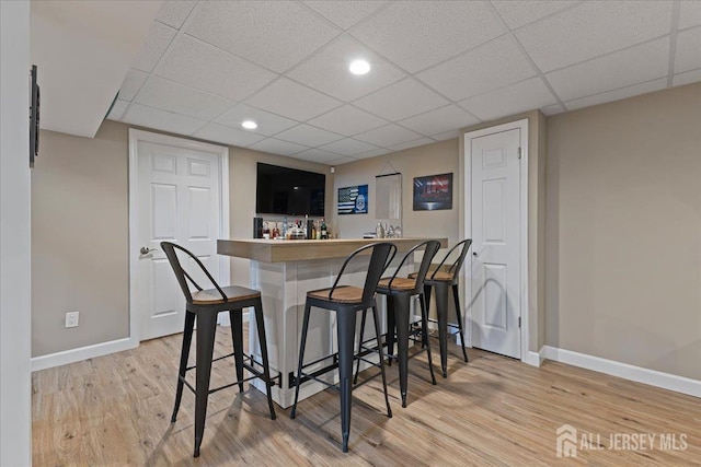indoor wet bar with baseboards, wood finished floors, a paneled ceiling, and recessed lighting