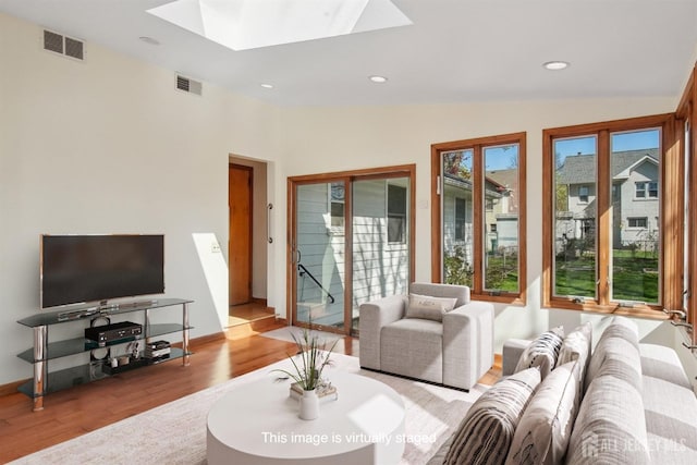 living area with a skylight, wood finished floors, baseboards, recessed lighting, and vaulted ceiling