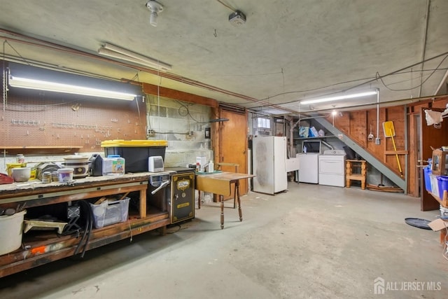 unfinished below grade area featuring washer and clothes dryer, a workshop area, and freestanding refrigerator