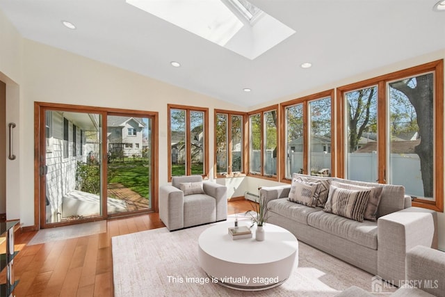 sunroom / solarium featuring a skylight, lofted ceiling, hardwood / wood-style floors, recessed lighting, and baseboard heating